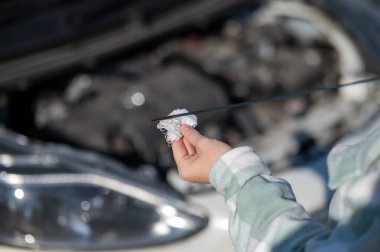 Araba motorunda yağ seviyesini kontrol eden kadın sürücünün ellerini kapatın.