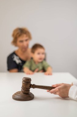 Hakim, elinde çocuk tutan yaşlı bir kadının arka planına vuruyor.