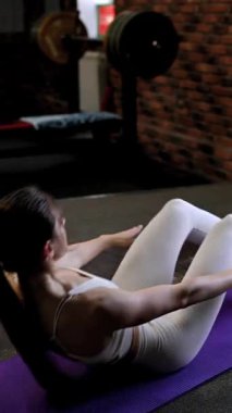 Beyaz kadın spor salonunda karın egzersizi yapıyor.