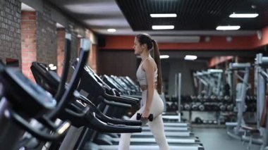 Kafkasyalı kadın spor salonunda dambıllarla yürüyordu.