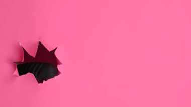 Siyah desenli vibratörlü, pembe kağıt arkaplanından çıkmış bir kadın eli. Boşluğu kopyala