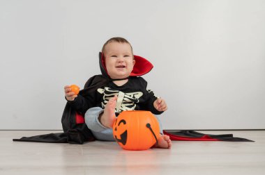 Beyaz arka planda şeker sepeti tutan Dracula Cadılar Bayramı kostümlü beyaz tatlı çocuk.