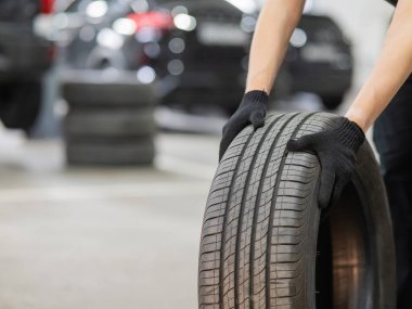 Eski araba lastiği tutan adam. Tekerlekli mekanik elleri kapat