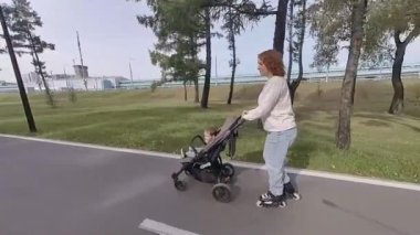 Beyaz kadın bebek arabasıyla küçük oğluyla paten kayıyor.