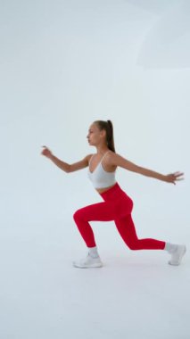 Beyaz arka plana atlayan genç bir kadın. Dikey video