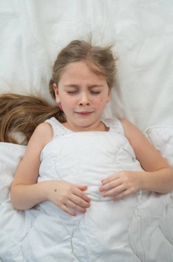 Küçük tatminsiz bir kızın yatakta yatışının üst görüntüsü. Dikey fotoğraf