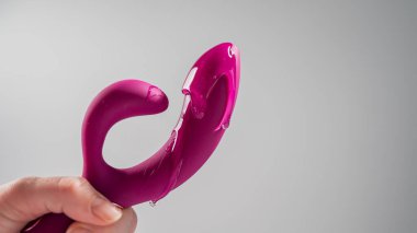 Lube pouring on pink dildo on white background