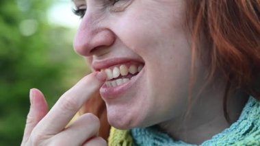 Beyaz kadın parmaklarıyla dişlerini karıştırıyor.