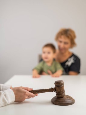 Hakim, elinde çocuk tutan yaşlı bir kadının arka planına vuruyor.