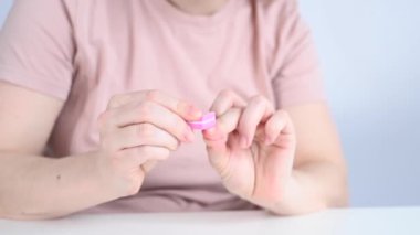 Beyaz kadın tırnaklarını törpüleyip cilalıyor.