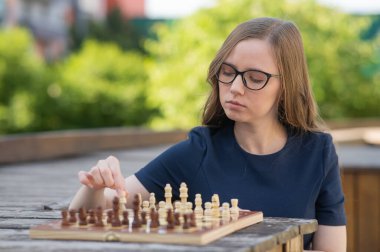 Beyaz kadın dışarıda satranç oynuyor.