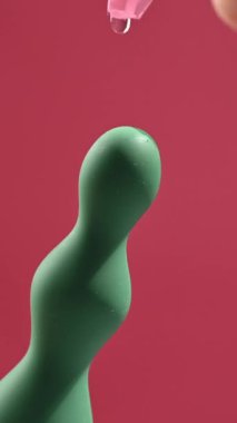 Pembe arka planda yeşil anal boncuklara yağ dökülüyor.