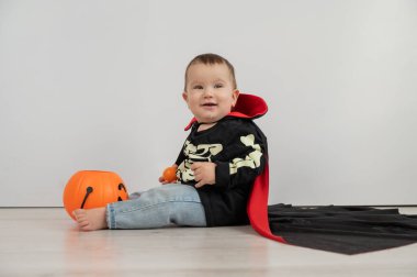 Beyaz arka planda şeker sepeti tutan Dracula Cadılar Bayramı kostümlü beyaz tatlı çocuk.