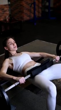 Beyaz kadın halterle kalça köprüsü yapıyor. Kalça darbesi