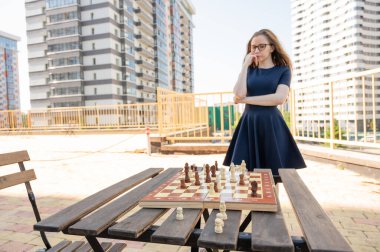 Beyaz kadın dışarıda satranç oynuyor.