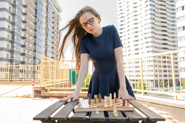 Beyaz kadın dışarıda satranç oynuyor.