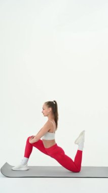 Beyaz arka plan üzerinde bölme egzersizleri yapan genç kadın