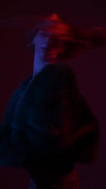 Young woman dancing high heels in red blue neon light. Vertical video