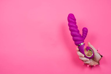 Pembe kağıttan yapılmış pembe seks oyuncağıyla dışarı çıkmış bir kadın eli. Boşluğu kopyala