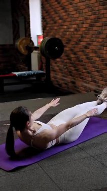 Beyaz kadın spor salonunda karın egzersizi yapıyor.