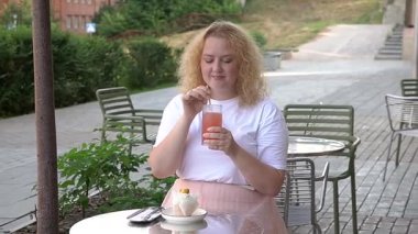 Şişman beyaz kadın dışarıda samandan kokteyl içiyor.