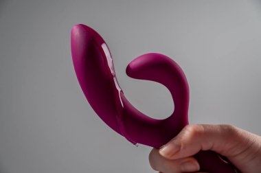 Lube pouring on pink dildo on white background