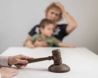 Hakim, elinde çocuk tutan yaşlı bir kadının arka planına vuruyor.