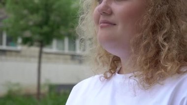 Fazla kilolu beyaz kadın yürürken patates kızartması yiyor.