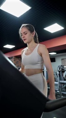 Beyaz kadın spor salonunda koşu bandında çalışmaya başladı.