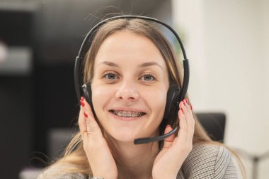 Diş teli takan bir kadın kulaklıkla konuşur. Yardım Masası