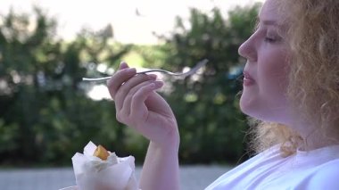 Caddedeki kafede kek yiyen şişman beyaz kadın.