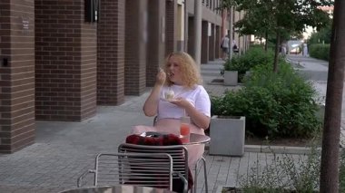 Caddedeki kafede kek yiyen şişman beyaz kadın.