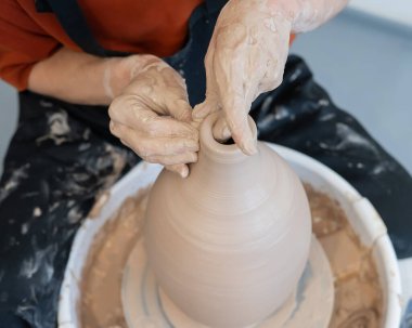 Çömlekçi elleriyle çömlekçi çarkında seramik vazo yaparken.