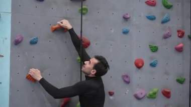 Beyaz adam tırmanma duvarında eğitim görüyor.