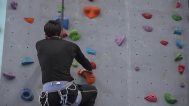 Beyaz adam tırmanma duvarında eğitim görüyor.