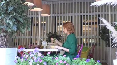 Beyaz kadın yazın kafede salata yiyor.