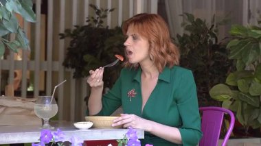 Beyaz kadın yazın kafede salata yiyor.