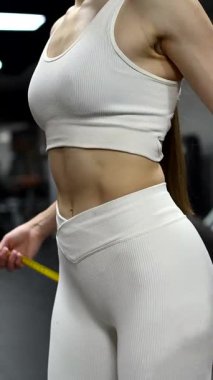 Beyaz kadın spor salonunda belini ölçüyor.