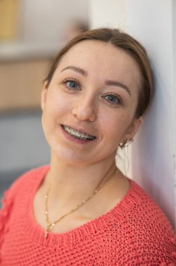 Dişlerinde diş teli olan gülümseyen beyaz kadın portresi.