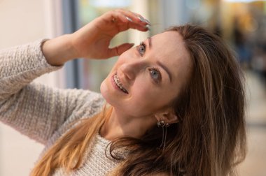 Dişlerinde diş teli olan suratsız bir kadının portresi.