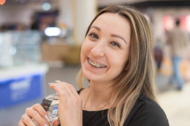 Dişlerinde diş teli olan beyaz kadın içme suyu içiyor.