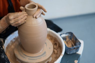 Çömlekçi elleriyle çömlekçi çarkında seramik vazo yaparken.