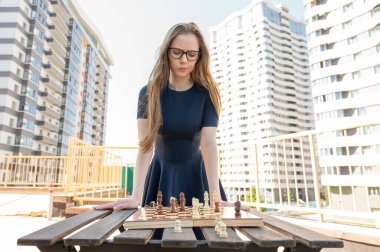 Beyaz kadın dışarıda satranç oynuyor.