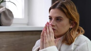 Beyaz kadın gergin bir şekilde masada oturuyor.