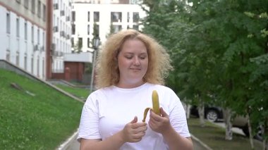 Yürürken muz yiyen şişman beyaz kadın.