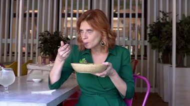 Beyaz kadın yazın kafede salata yiyor.