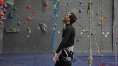 Beyaz adam tırmanma duvarında talk pudrası kullanıyor.