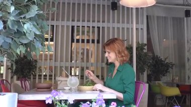 Beyaz kadın yazın kafede salata yiyor.