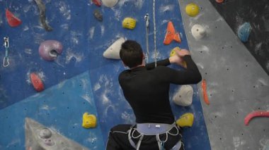 Beyaz adam tırmanma duvarında eğitim görüyor.