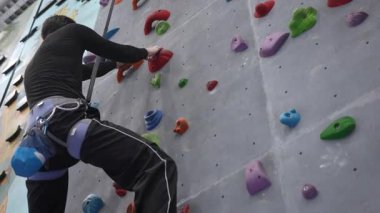Beyaz adam tırmanma duvarında eğitim görüyor.